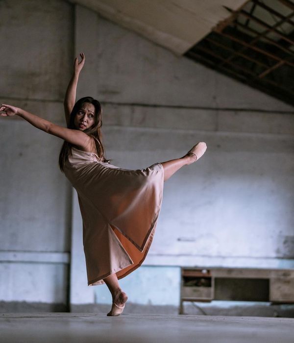 Person in a dynamic, fluid motion pose in a minimalist space.
